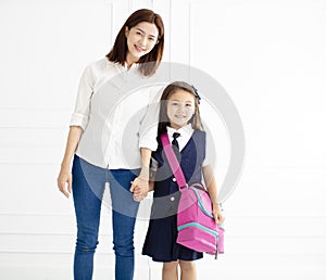 Mother holding hand of daughter ready go to school