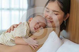 The Asian mother hug her young son so that she could have a good sleep in the bedroom at home, Represents love and family