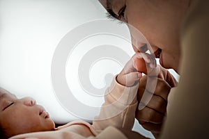 Asian mother kissing hand, her 1-month-old baby newborn daughter