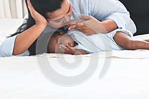 Asian mother kissing her 2-month-old baby newborn son