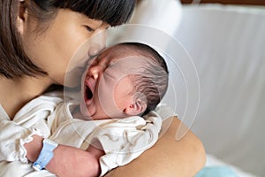 Asian mother kissing her newborn baby