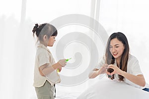Asian mother and little girl daughter child blowing soap bubbles in the living room, have fun together in a cozy home, happy