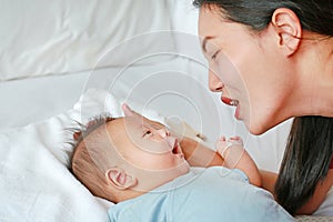 Asian mother lying with her son on white fur background. Close-up of baby and mom