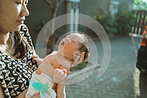 Asian mother with newborn sunbathing baby