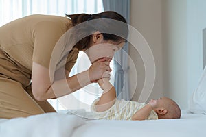 Asian mother playing with her newborn baby in bedroom at home. to promote family relations and good development of the baby