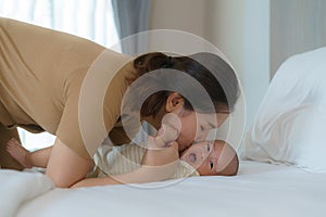 Asian mother playing with her newborn baby in bedroom at home. to promote family relations and good development of the baby