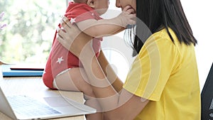 Asian mother playing with her newborn baby`s on the table in the office room