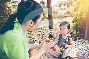 Asian mother playing plastic trumpet pipe with her daughter. Vintage tone.