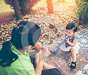 Asian mother playing plastic trumpet pipe with her daughter. Vintage tone.