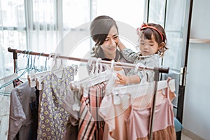 asian mother purchasing a clothes while shopping with her toddler baby