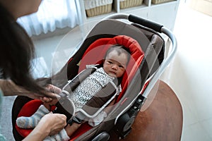 Asian mother putting baby into seat