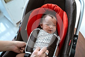 Asian mother putting baby into seat