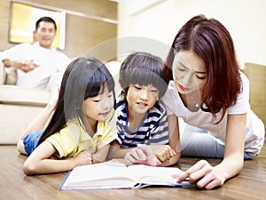 Asian mother reading book with two children