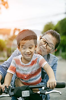 Asian mother and son practice to riding bicycle in public park