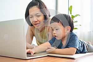 Asian mother and son using Laptop while practicing yoga exercise on the floor