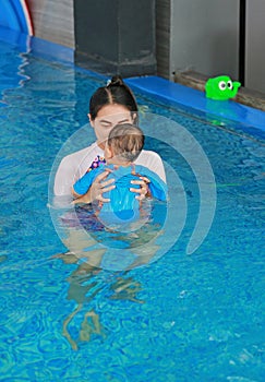 Asian mother teaching baby boy in swimming pool