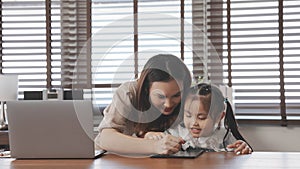 Asian mother teaching daughter help drawing togther after back form school at home photo