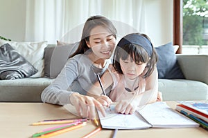 Asian mother teaching her cute kid daughter to studying at home