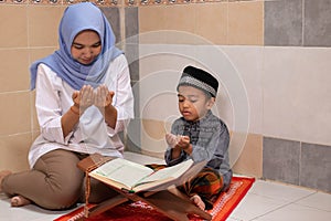 An Asian mother is teaching her son to read Al-Qur`an