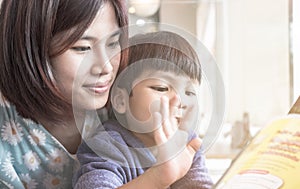 Asian Mother is teaching her son to read a book