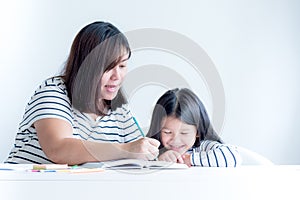 Asian mother is teaching a 6 year old daughter to learn to write and read