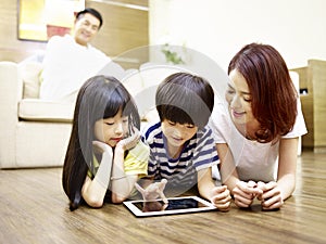 Asian mother and two children using digital tablet together