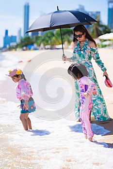 Asian mother and two daughters take walk on the beach. Travel with family during the holidays. Summer time.