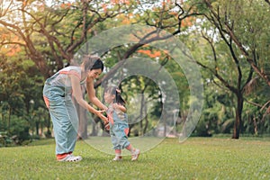 Asian mother walking with daughter in park, Happy family in the park evening light