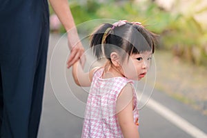Asian mother walking with daughter in park, Parents hold the baby's hands.