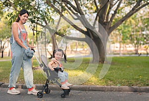 Asian mother walking with daugther in stroller in park, Happy family concept