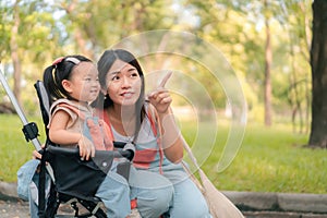 Asian mother walking with daugther in stroller in park, Happy family concept