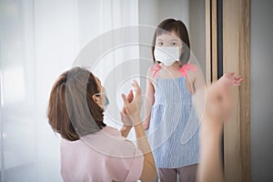 Asian mother wearing wearing to her daughter healthy face mask