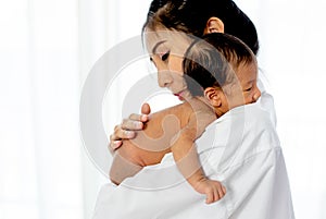 Asian mother with white shirt place upon the shoulder of little newborn baby after give milk and the baby look sleepy