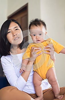 Asian mother woman carrying and hugging baby boy at bedroom in the morning,Mother`s day concept
