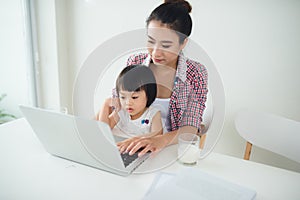 Asian mother woman with a her daughter working at the computer