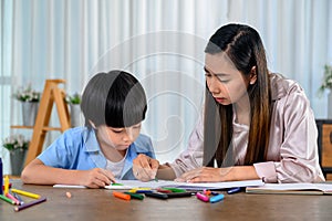 Asian mother work home together with son. Mom and kid drawing picture and color painting art. Woman lifestyle and family