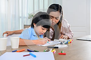 Asian mother work home together with son. Mom and kid drawing picture and color painting art. Woman lifestyle and family