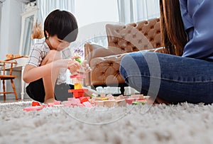 Asian mother work home together with son. Mom and kid play color wooden block. Child lifestyle