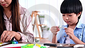 Asian mother work home together with son. Mom and kid play dough. Child creating plasticine clay model. Woman lifestyle and family