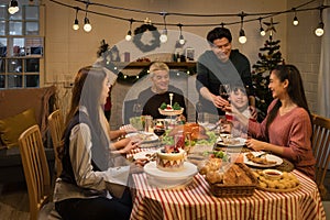 an asian multi-generational family joyfully gathers around a festive dinner table, celebrating christmas or thanksgiving, sharing