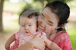 Asian mum and little child - young happy and beautiful Korean woman playing on city park with adorable and cheerful baby girl in