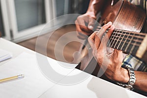 Asian musician playing guitar is composing. Music teacher.