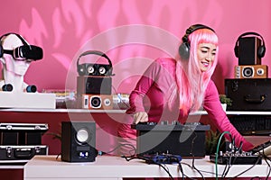 Asian musician standing at dj table wearing headphones while playing techno music at professional turntables