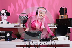 Asian musician standing at dj table wearing headset while playing techno music at professional mixer console in club