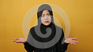 Asian muslim businesswoman wearing hijab shows refusal or denial gesture, shoulder shrug, I don`t know expression