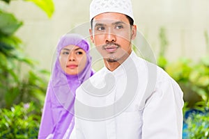 Asian Muslim couple, man and woman, praying at home