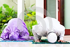 Asian Muslim couple, man and woman, praying at home photo