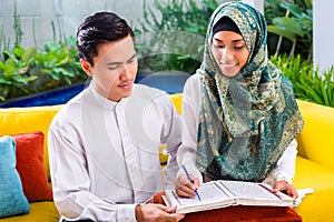 Asian Muslim couple reading together Koran or Quran