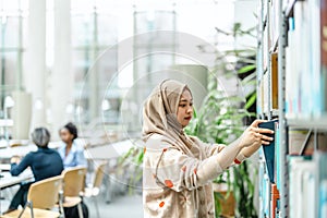 Asian muslim female student standing in a library