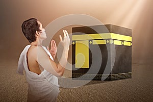 Asian Muslim man in ihram clothes standing and praying in front of the Kaaba